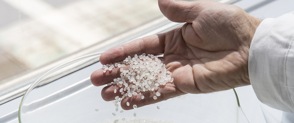 A hand holds polymers pellets